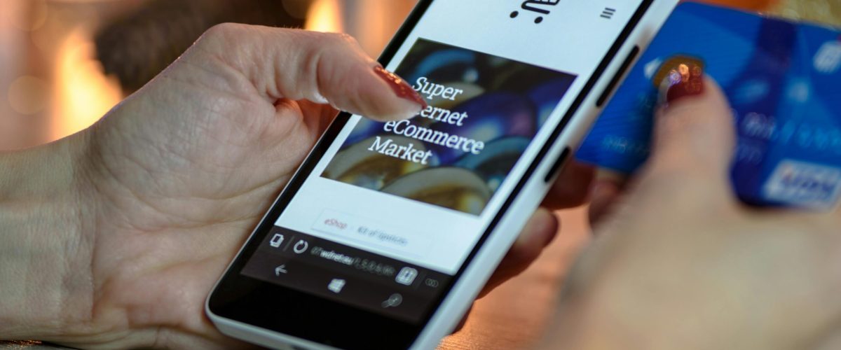 pexels-photo-230544-230544 Woman using smartphone for online shopping with credit card in hand, festive background lighting.